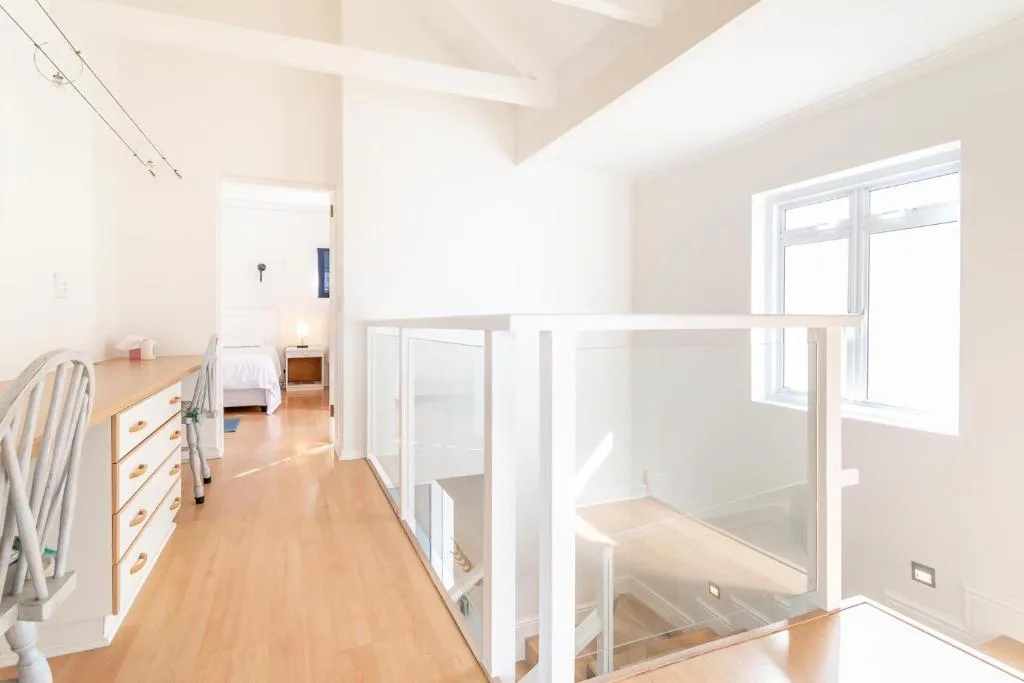 Bright modern bedroom with wooden floors and large windows