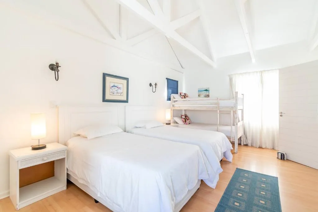 Bright bedroom with double bed, loft bunk, white walls and wooden floors