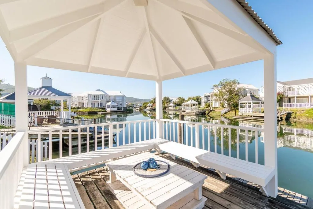 Shaded deck with white railings overlooking canal and waterfront homes