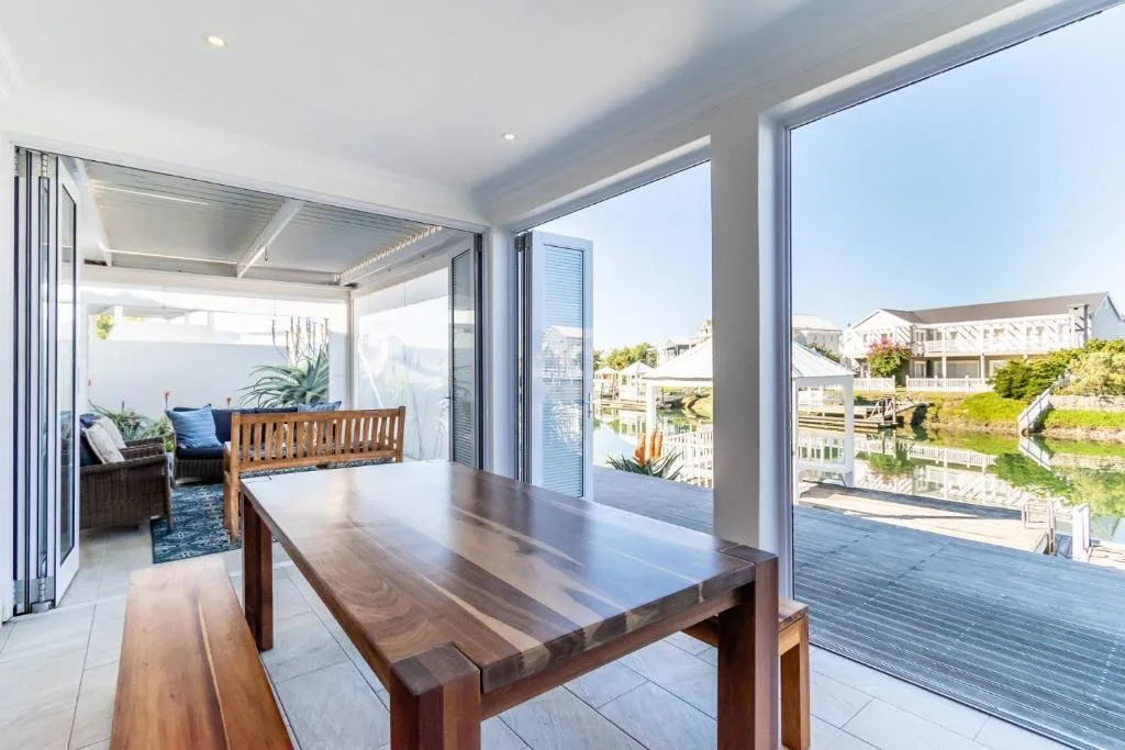 Modern covered deck with dining table overlooking canal waterfront