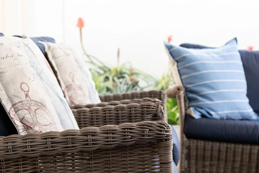 Wicker outdoor furniture with cushions and plants on a patio