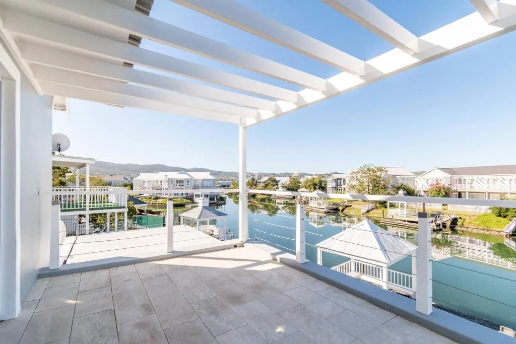 Spacious waterfront deck with pergola overlooking canal and houses
