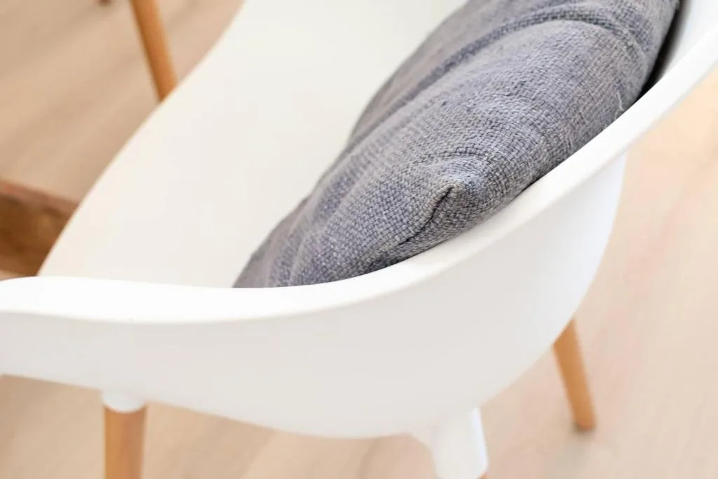 Close-up of modern white chair with gray upholstered seat cushion