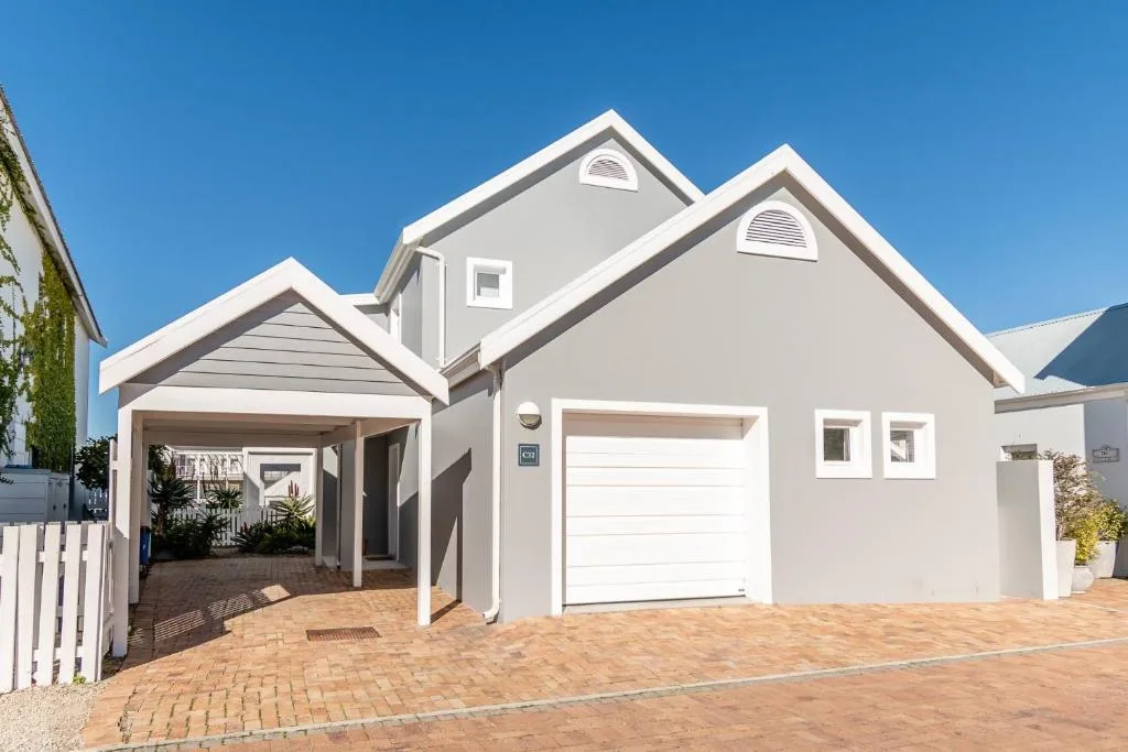 Modern white house with garage and carport under clear blue sky