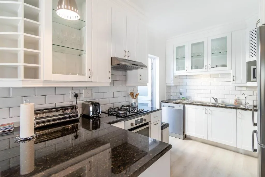Modern white kitchen with gas stove, dark countertops, and stainless steel appliances