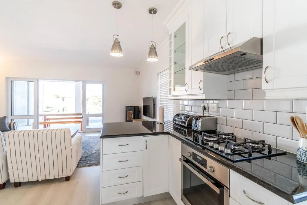 Modern white kitchen with gas stove, black countertops, and pendant lighting