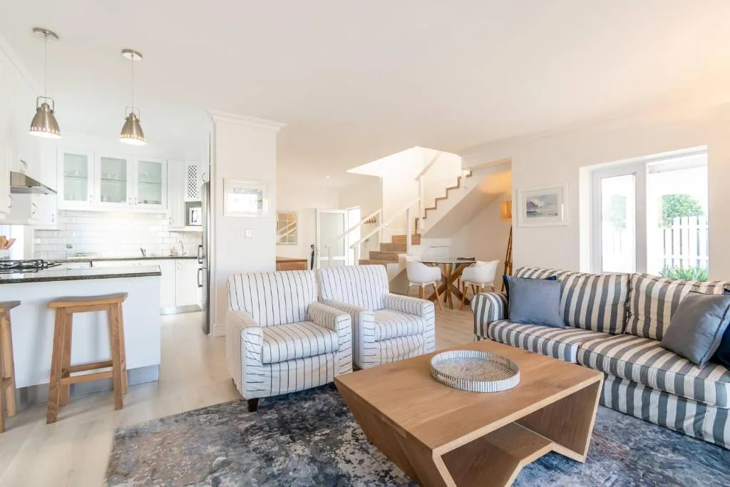 Bright open-plan lounge with striped armchairs and sofa, wooden coffee table