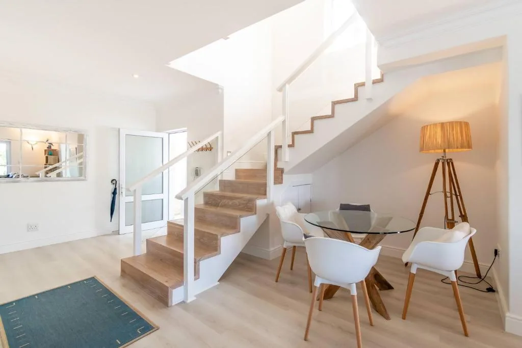 Modern open-plan living space with staircase, dining table, and contemporary furnishings