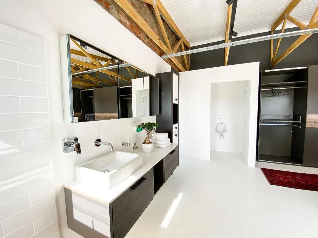 Modern bathroom with vanity sink, large mirror, and exposed wooden ceiling beams