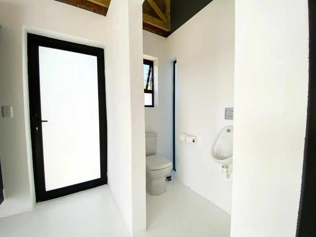 Modern bathroom with white walls, toilet, and wall-mounted urinal