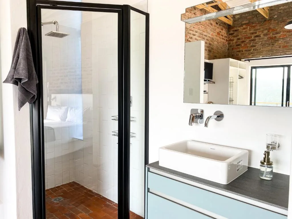 Modern bathroom with walk-in shower, vessel sink, and exposed brick ceiling