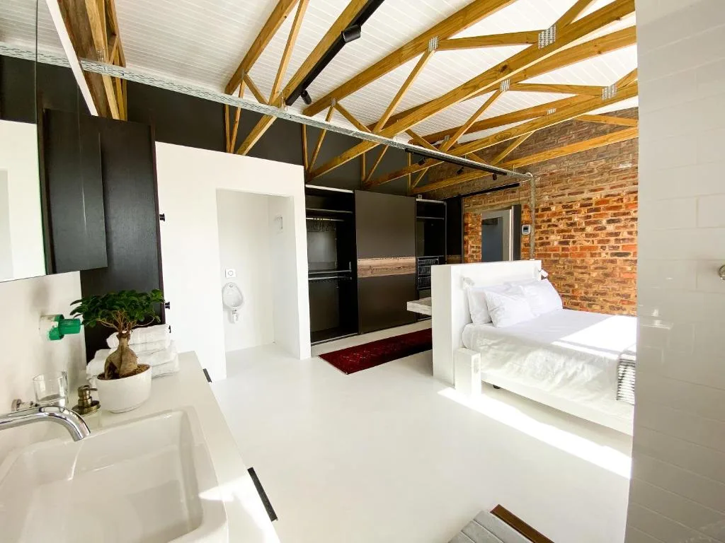 Modern studio bedroom with exposed brick walls and wooden beams