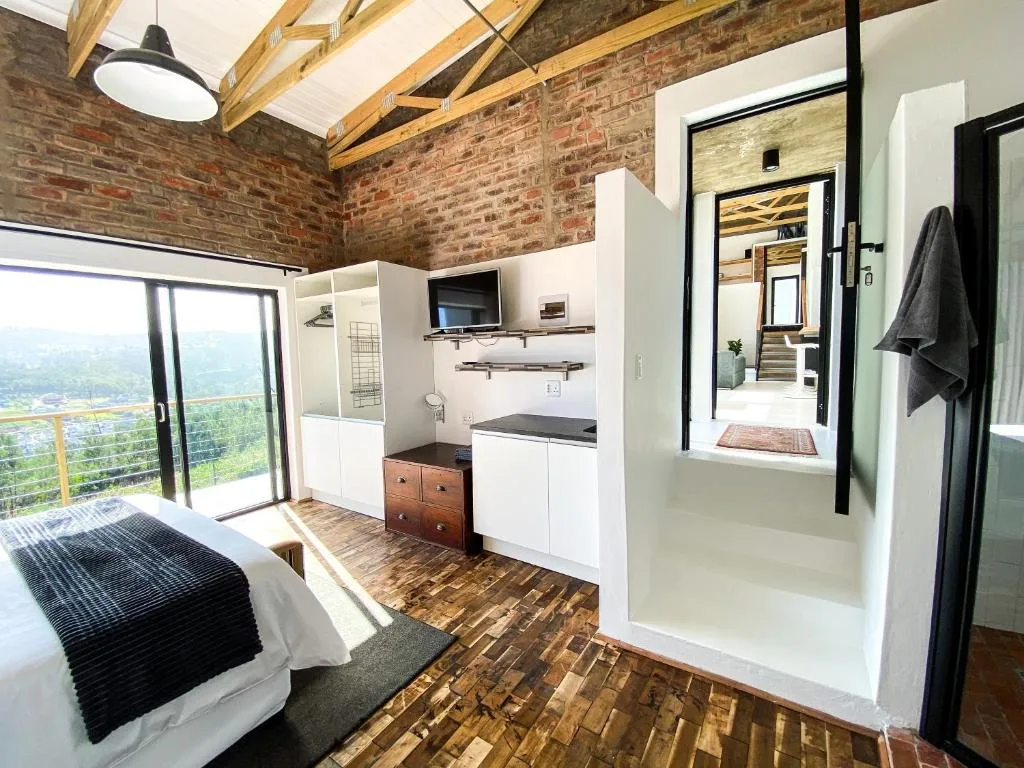 Bedroom with bed, kitchenette, and panoramic window view of lagoon