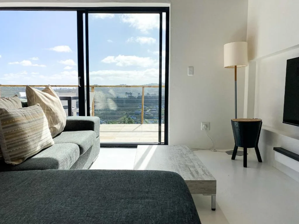 Bright bedroom with water views through glass doors and modern furnishings