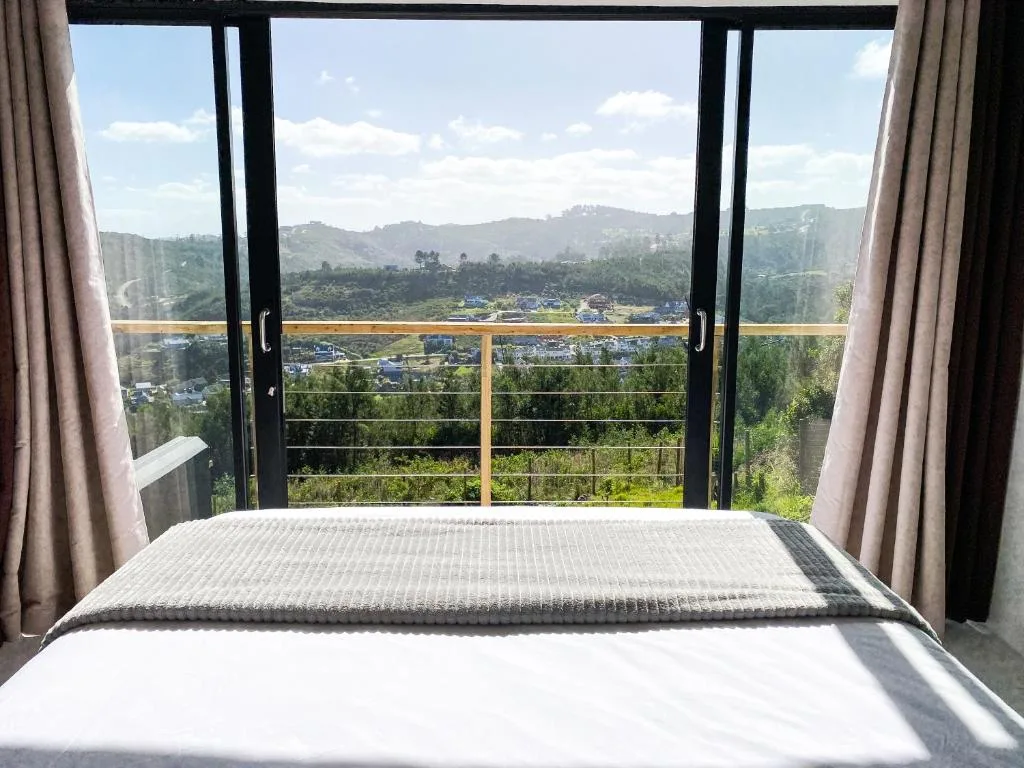 Bed with valley and mountain views through open glass doors