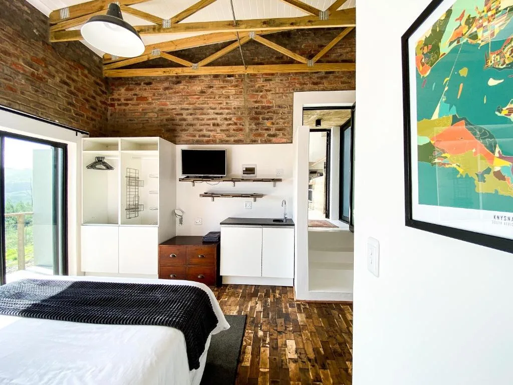 Spacious bedroom with bed, kitchenette, exposed brick and wooden beams