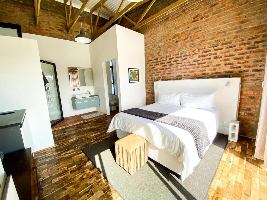Spacious bedroom with exposed brick walls and en-suite bathroom visible