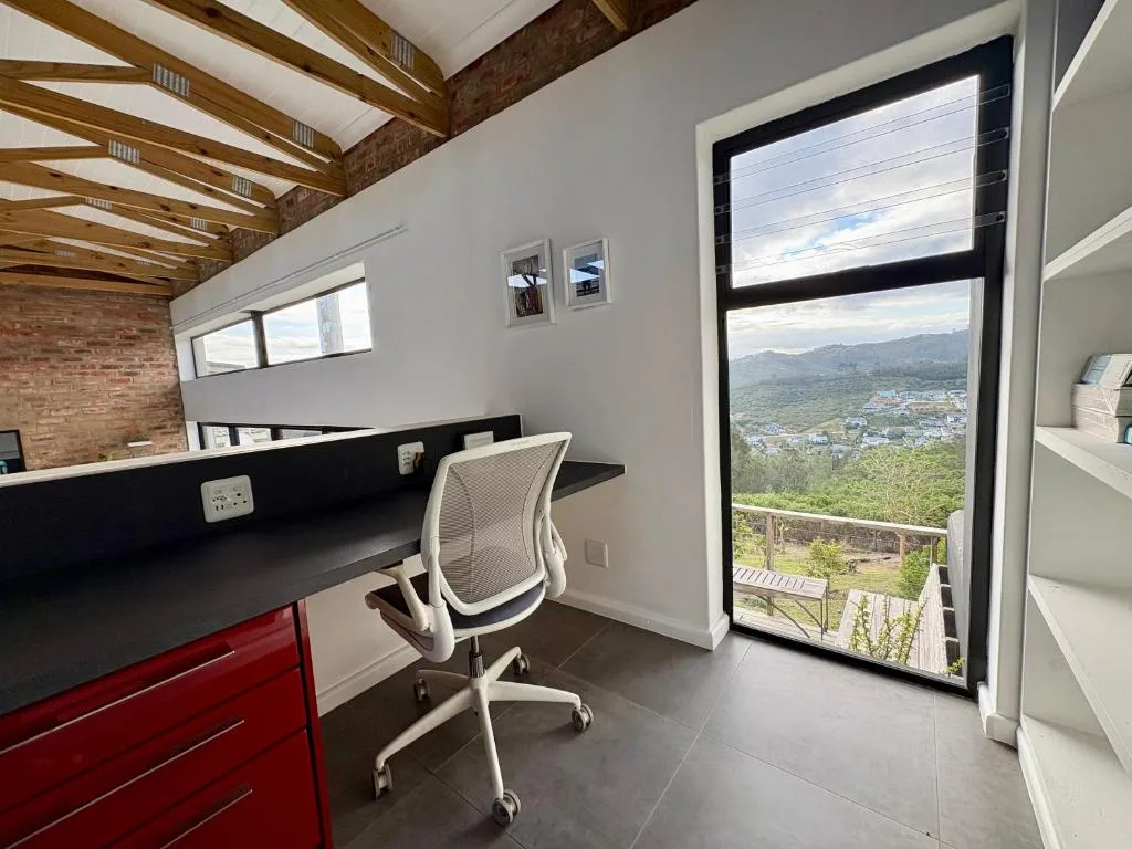 Modern home office with desk, chair, and expansive mountain view through glass doors