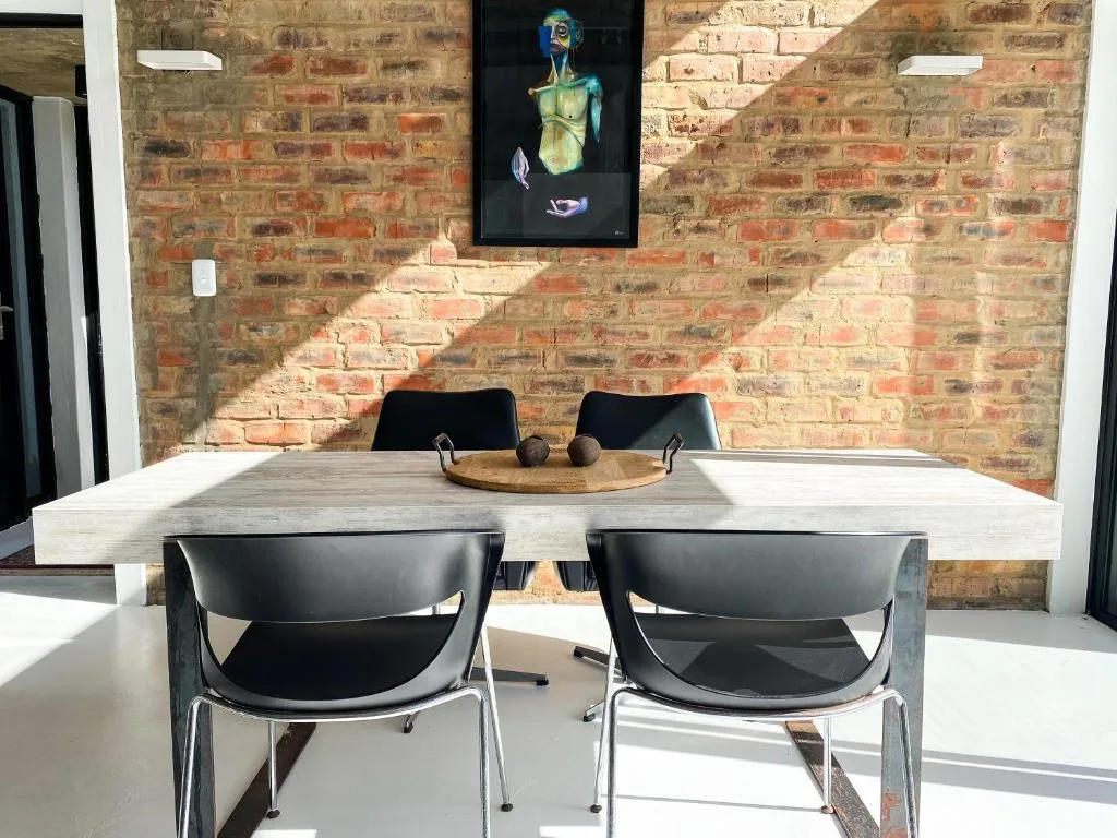 Modern dining table with black chairs against exposed brick wall