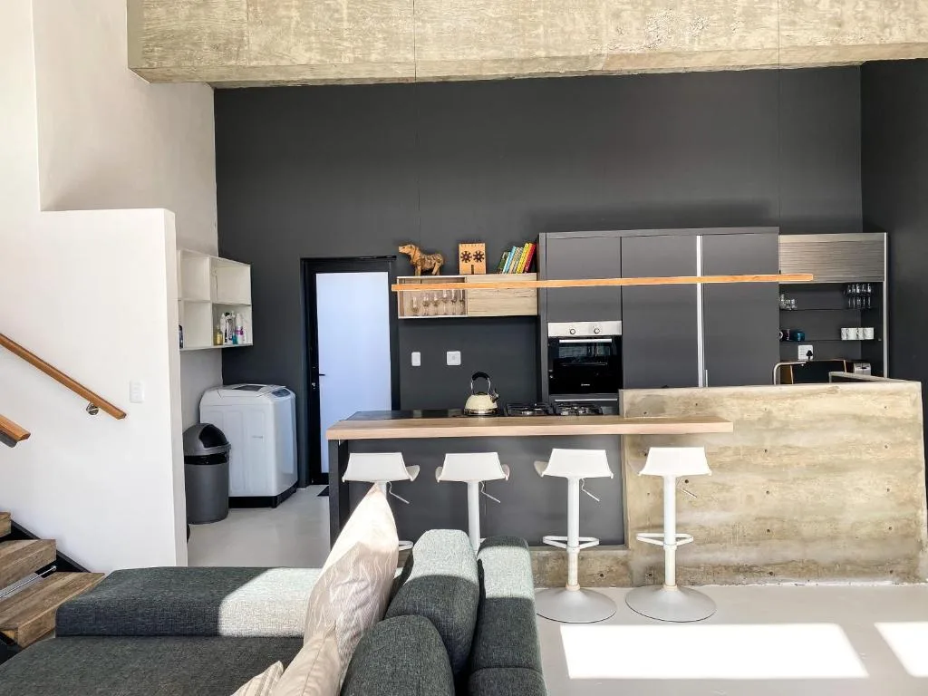 Modern open-plan kitchen with dark cabinetry, wooden counters, and bar seating