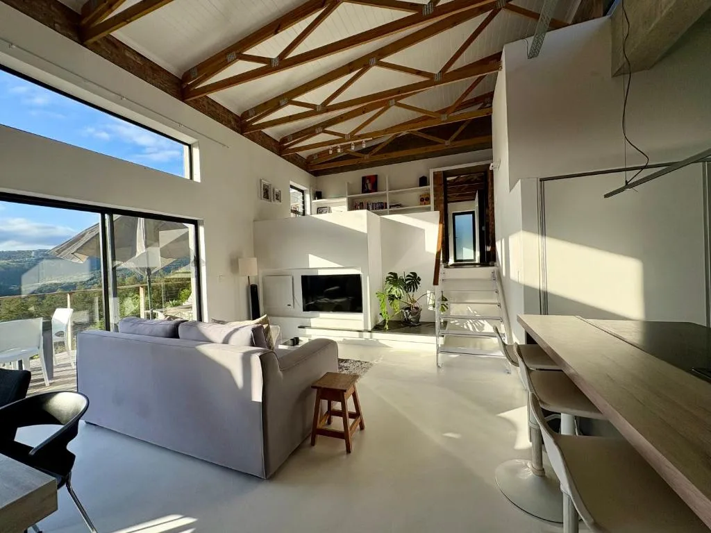 Open-plan lounge with cream sofa, fireplace, and expansive windows overlooking lagoon