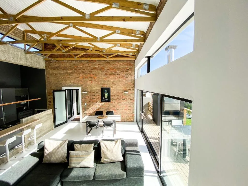 Modern lounge with gray sofa, brick feature wall, and large glass doors opening to deck