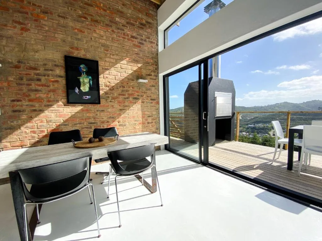 Modern living space with brick walls, dining table, and panoramic windows overlooking mountains