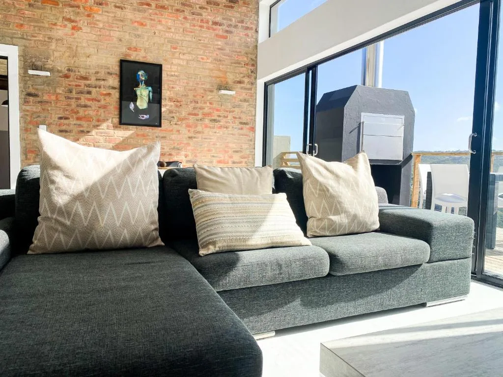 Modern lounge with gray sofa, patterned cushions, exposed brick wall, and sea views