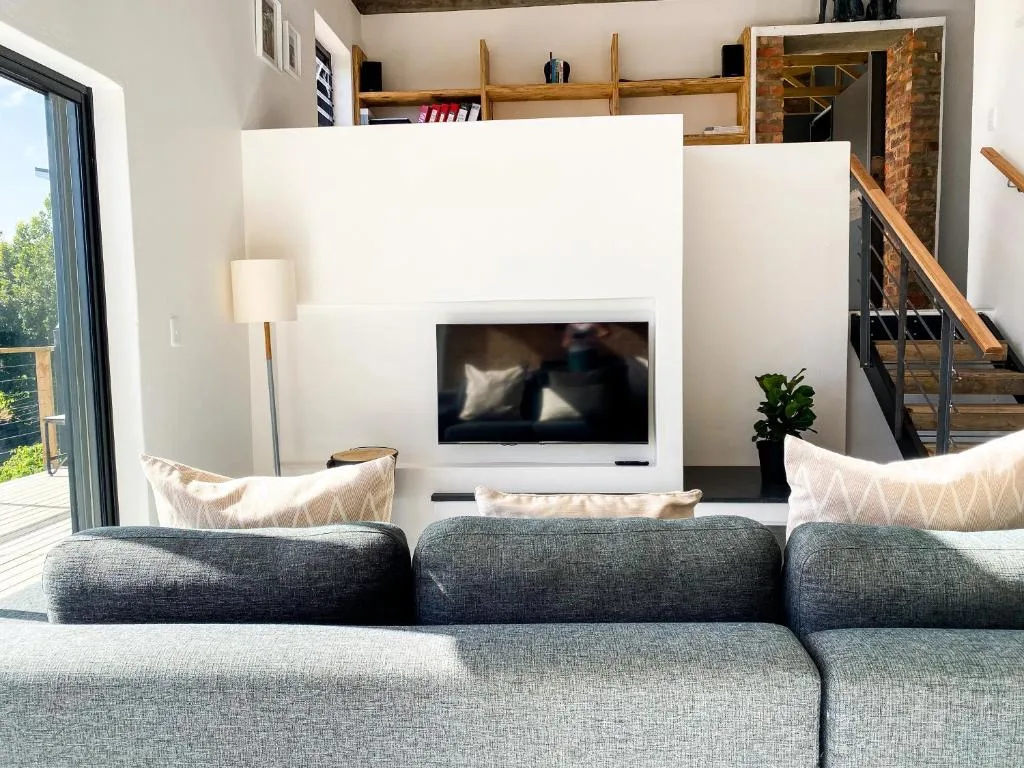 Modern lounge with gray sectional sofa facing wall-mounted TV and deck access