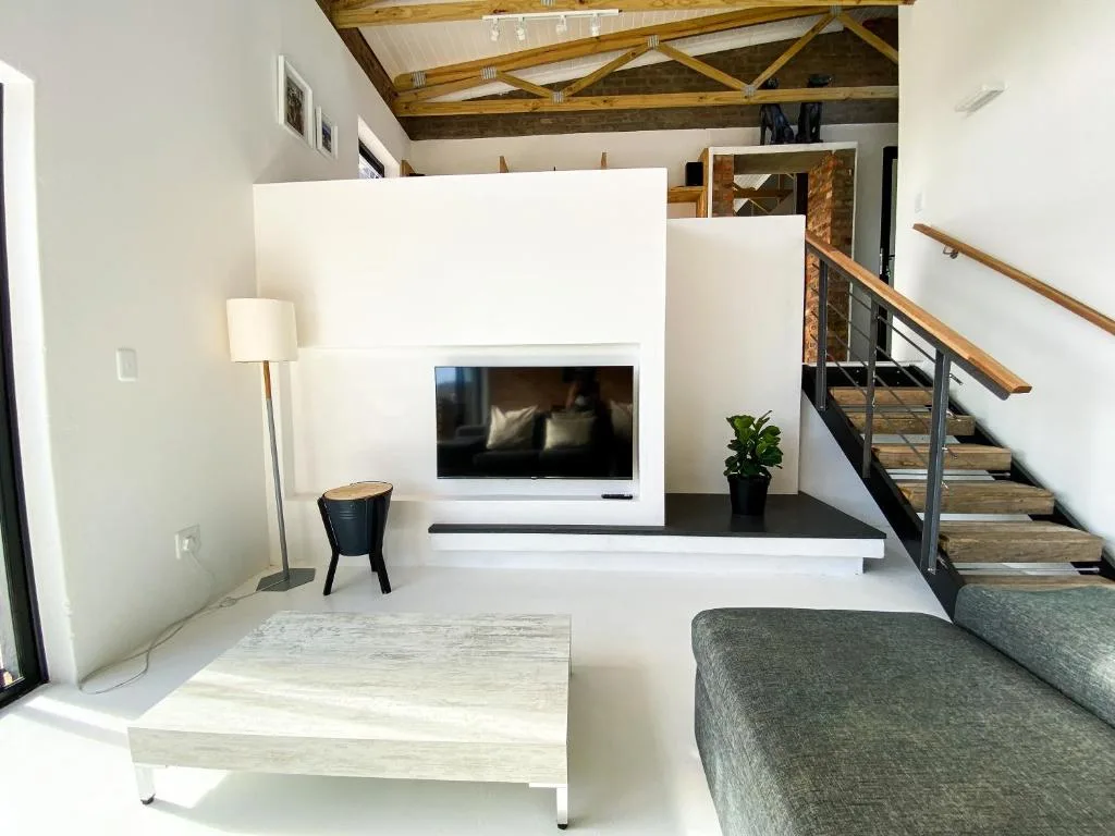 Modern living room with TV, sofa, coffee table, and wooden staircase