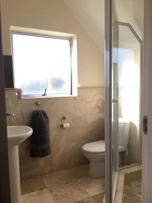Modern bathroom with toilet, pedestal sink, and window overlooking Knysna