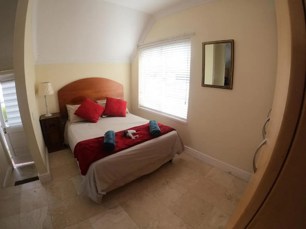 Bright bedroom with red-cushioned headboard, red pillows, and natural light from window