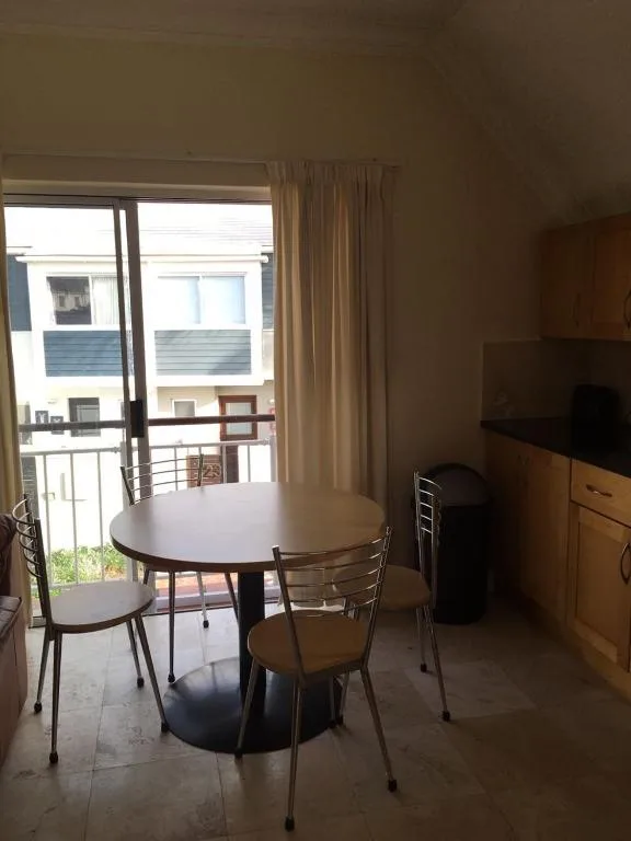 Round dining table with chairs beside glass doors opening onto balcony