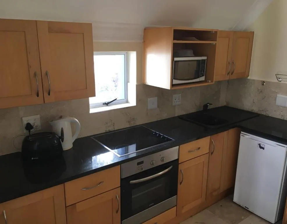 Kitchen with wooden cabinetry, black countertops, stove, and white appliances