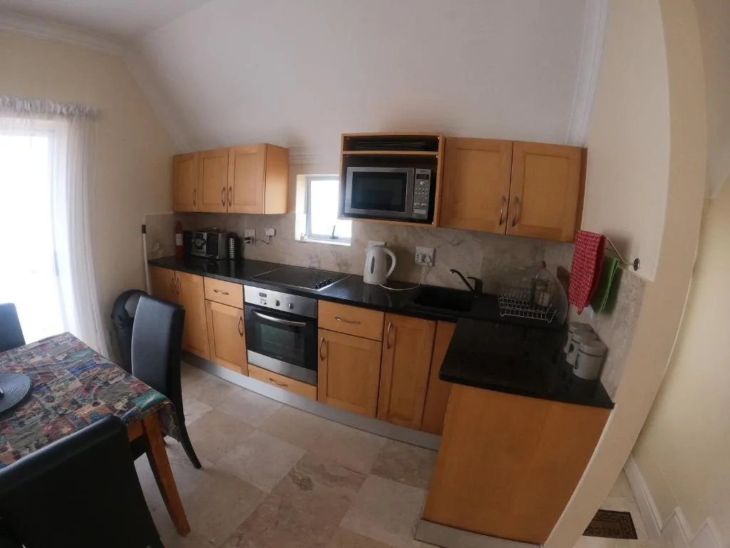 Compact kitchen with wooden cabinetry, black countertop, and stainless steel appliances