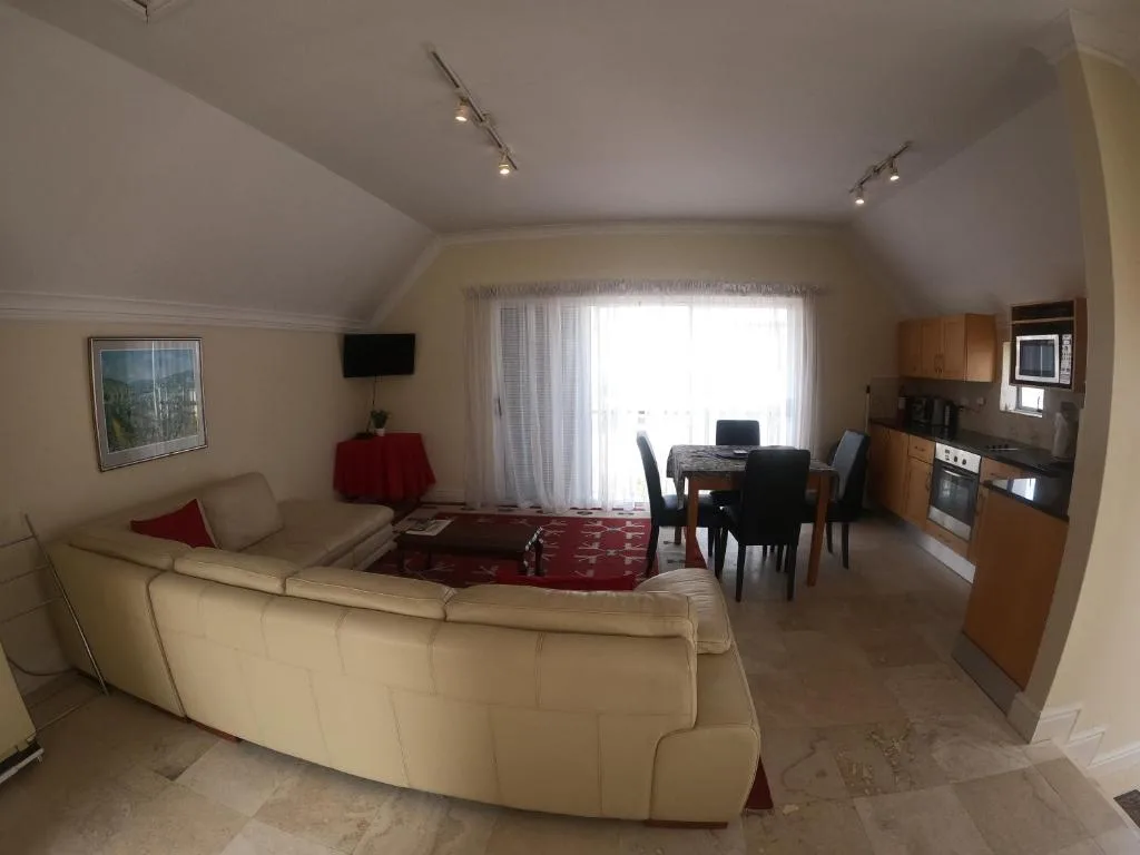Open-plan lounge with cream curved sofa, TV, and natural light from windows