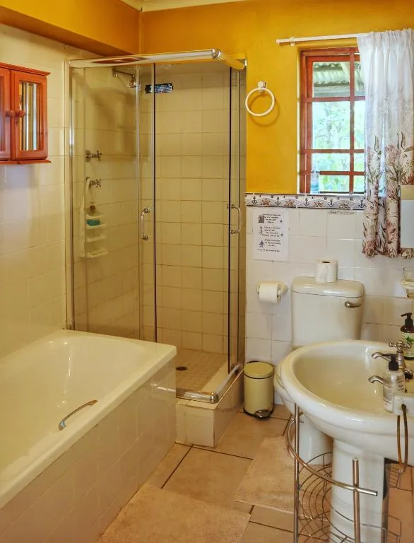 Bright yellow bathroom with shower enclosure, bathtub, and pedestal sink