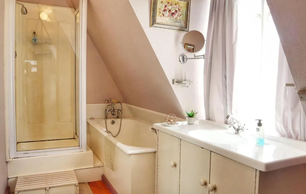 Bright attic bathroom with shower, bathtub, vanity, and mirror
