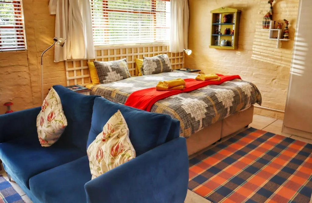 Bright bedroom with queen bed, blue armchair, patterned rug, and wooden headboard