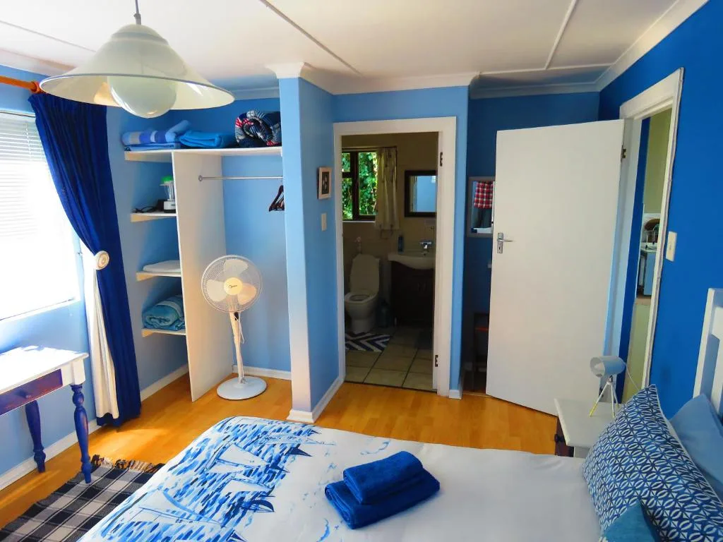 Bright blue bedroom with wooden floors and en-suite bathroom access