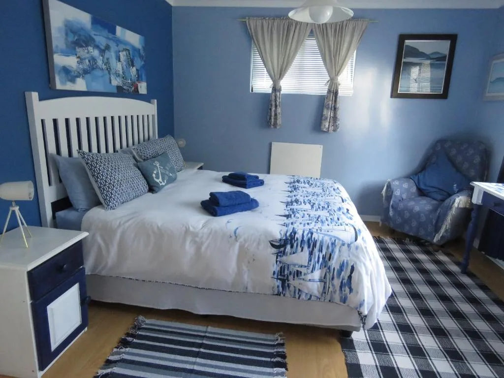 Bright blue bedroom with white bed, nautical decor, and comfortable seating area