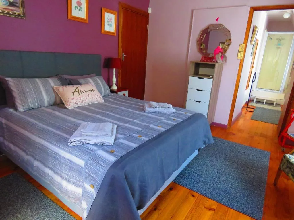 Bright bedroom with purple walls, queen bed, and wooden flooring throughout
