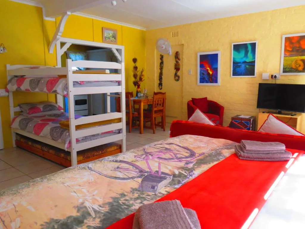 Bright yellow bedroom with bunk beds, red sofa, and wall art