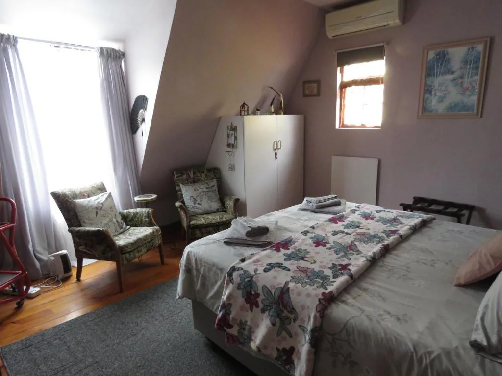 Spacious bedroom with twin beds, floral bedding, and reading chairs by window