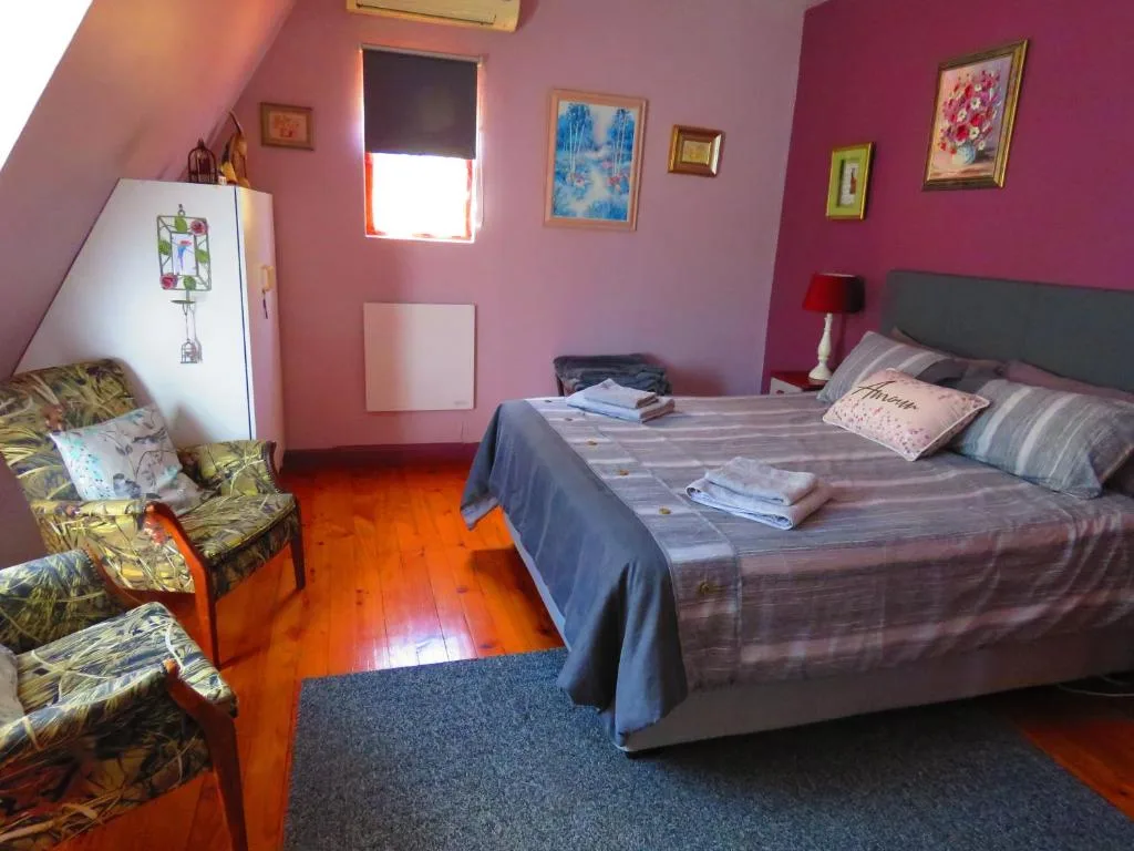 Bright pink bedroom with queen bed, seating area, and colorful wall art