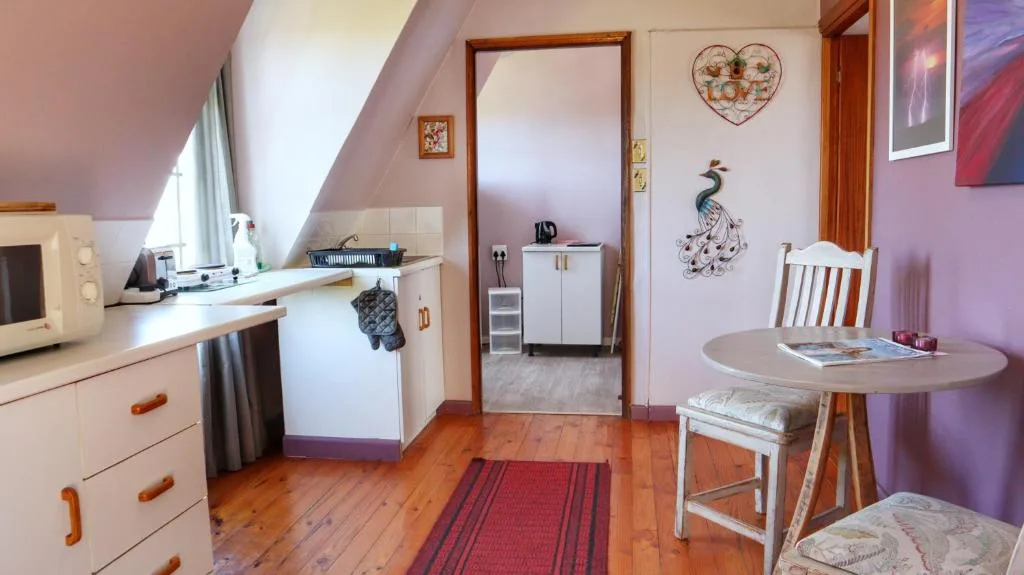Cozy attic bedroom with purple walls, kitchenette, round table and decorative touches