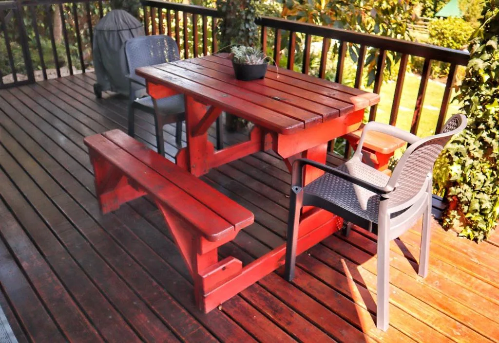 Outdoor deck with red picnic table and mixed seating surrounded by greenery