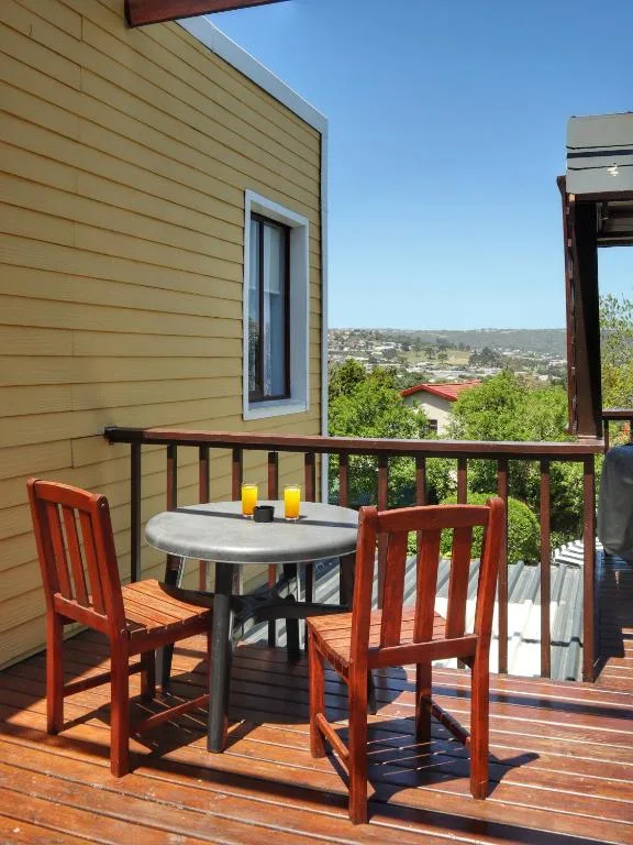 Outdoor deck with dining table and red chairs overlooking town valley