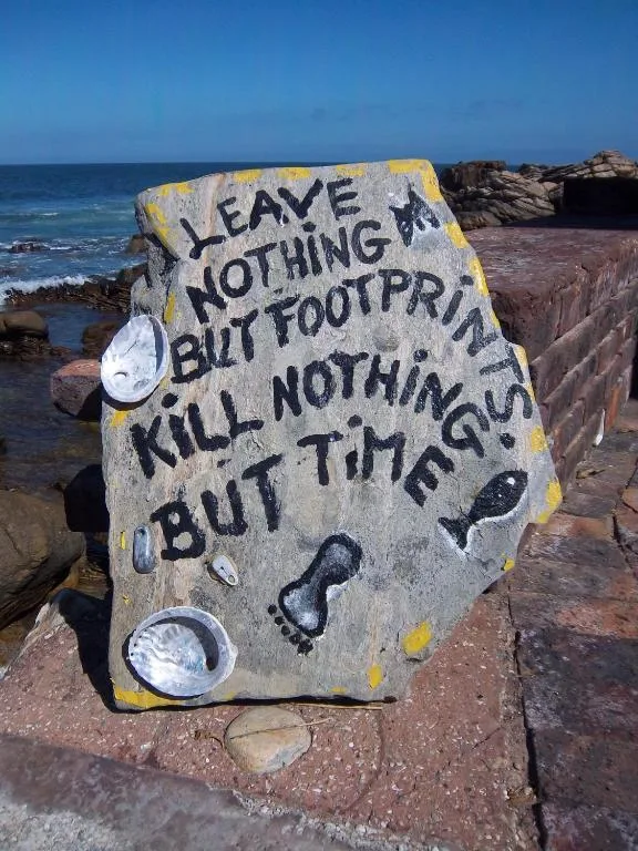 Coastal sign with environmental message on rocky Knysna shoreline