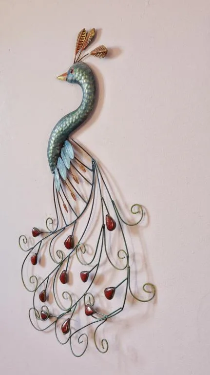 Ornamental peacock wall sculpture with turquoise body and dangling red beads